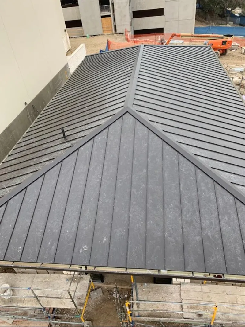 Commercial metal roof construction with crane equipment in Kaser